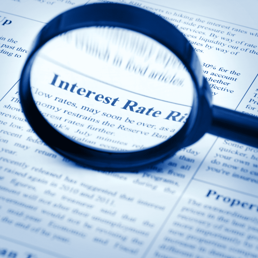 Photo of magnifying glass zooming in on the words "Interest Rates" on a newspaper.