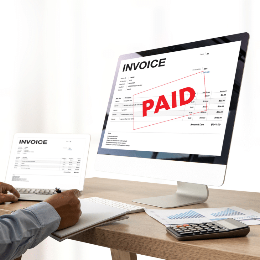 Person working in office with a computer displaying a paid invoice.